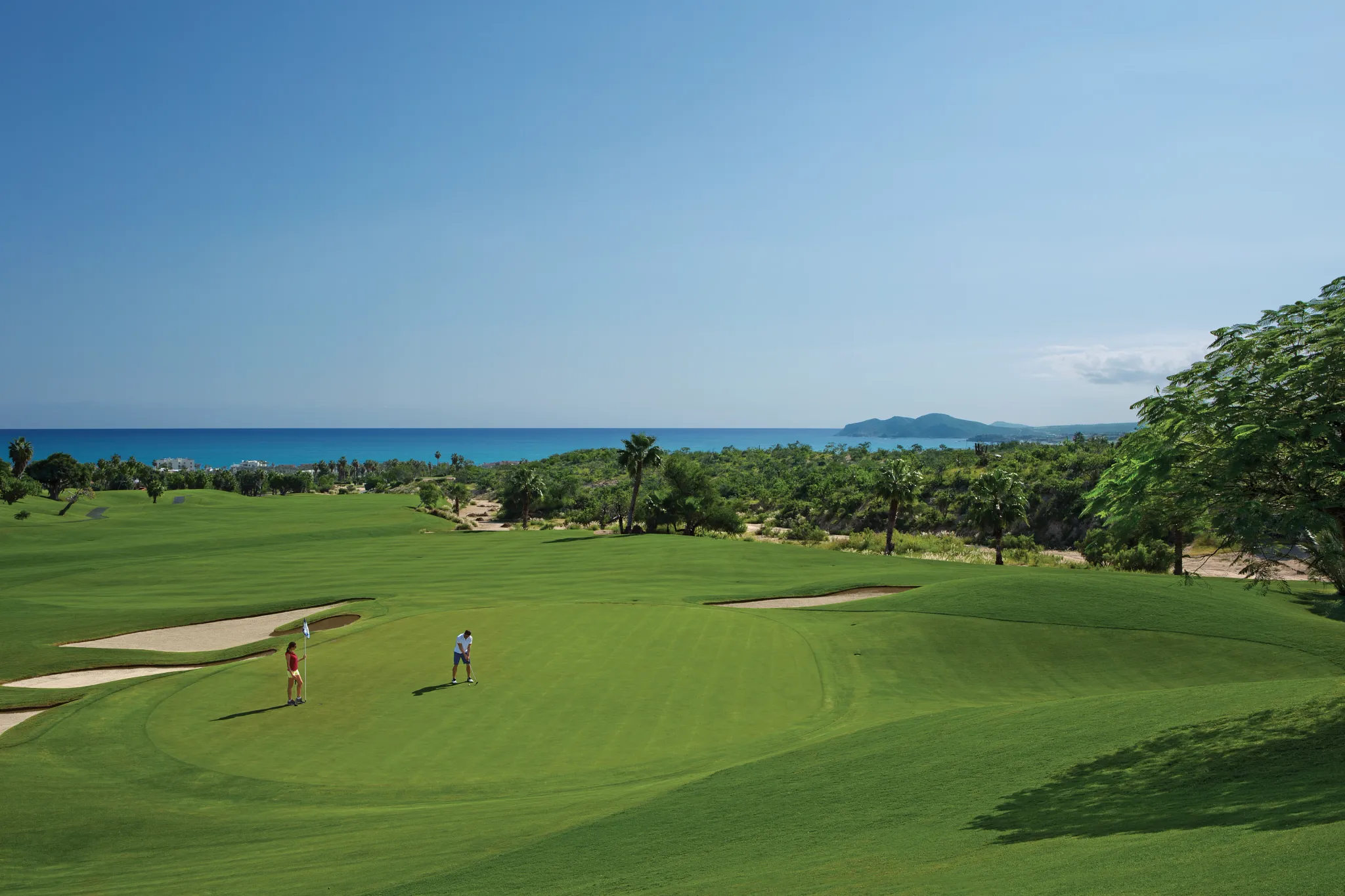 Golfers playing on the Cabo Real Golf Course overlooking the Sea of Cortez near Dreams Los Cabos Suites Golf Resort & Spa.