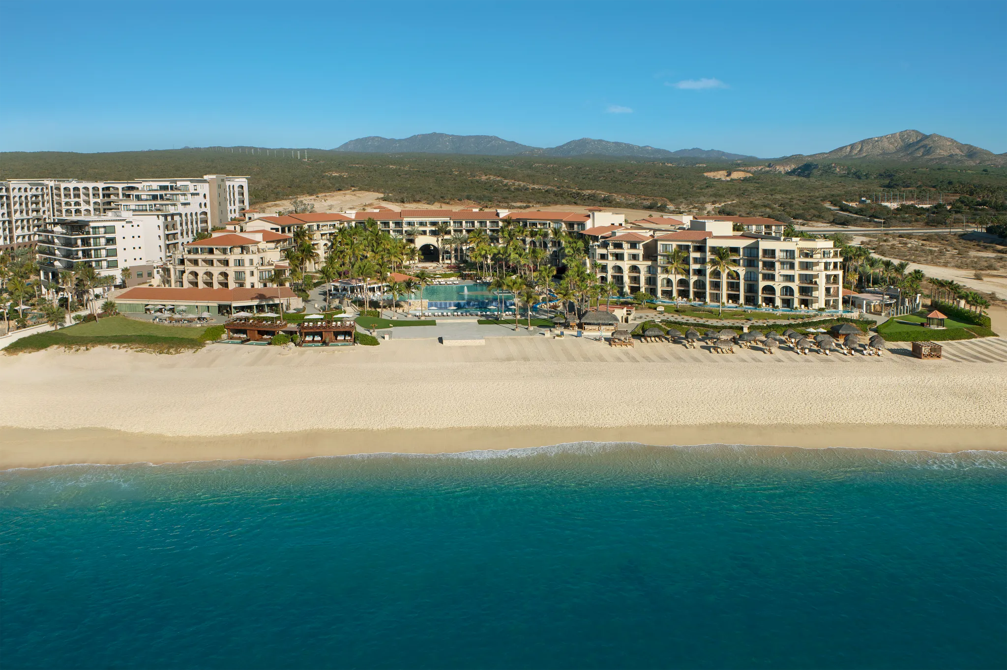 Aerial view of Dreams Los Cabos Suites Golf Resort & Spa beachfront resort with pools, palm trees, and the Sea of Cortez.