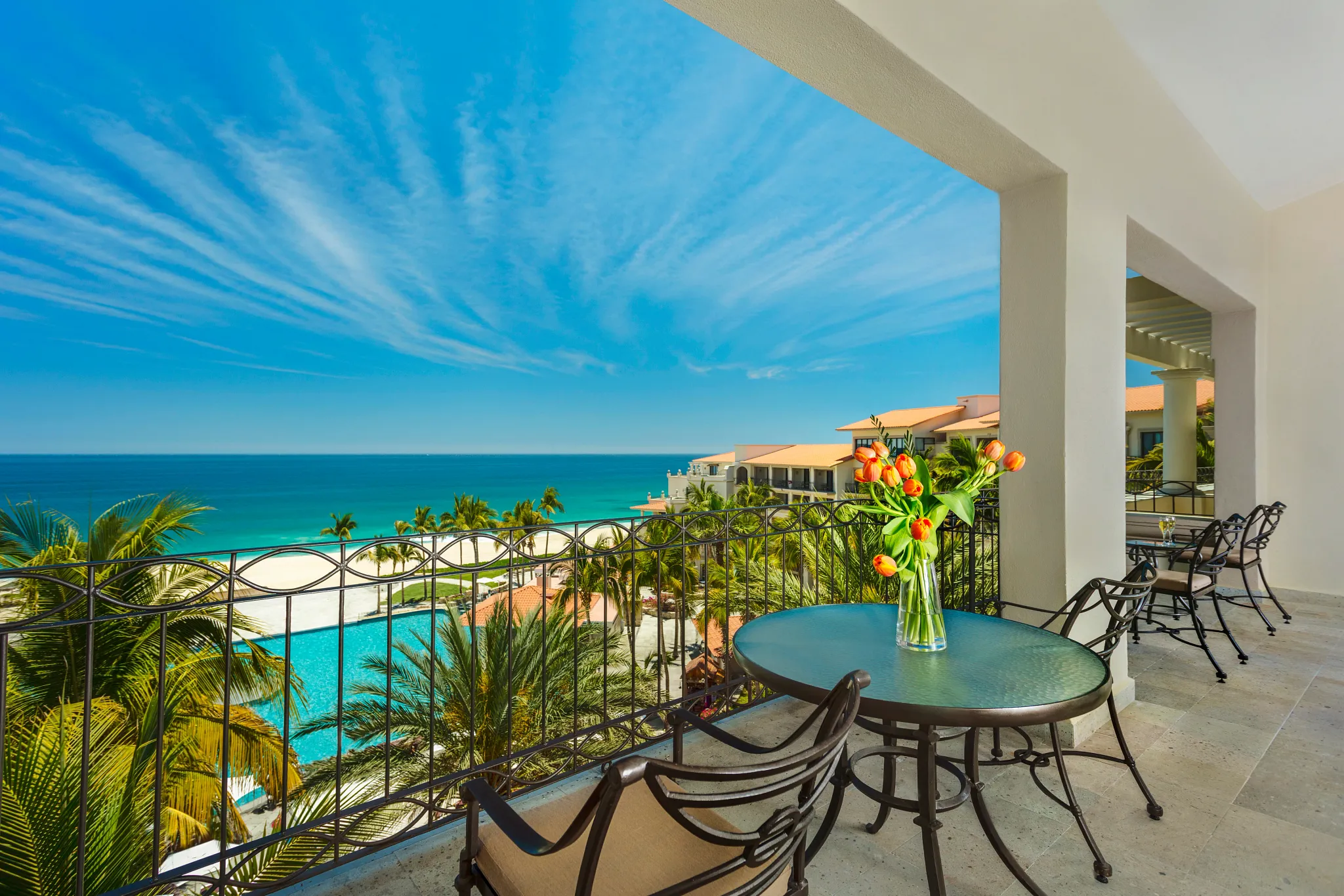 Preferred Club One Bedroom Suite Ocean View balcony with table and chairs overlooking pool, beach, and Sea of Cortez at Dreams Los Cabos.